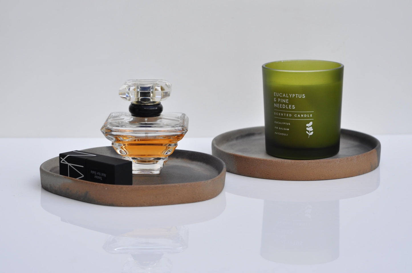 Perfume bottle and candle on a white surface with a neutral background