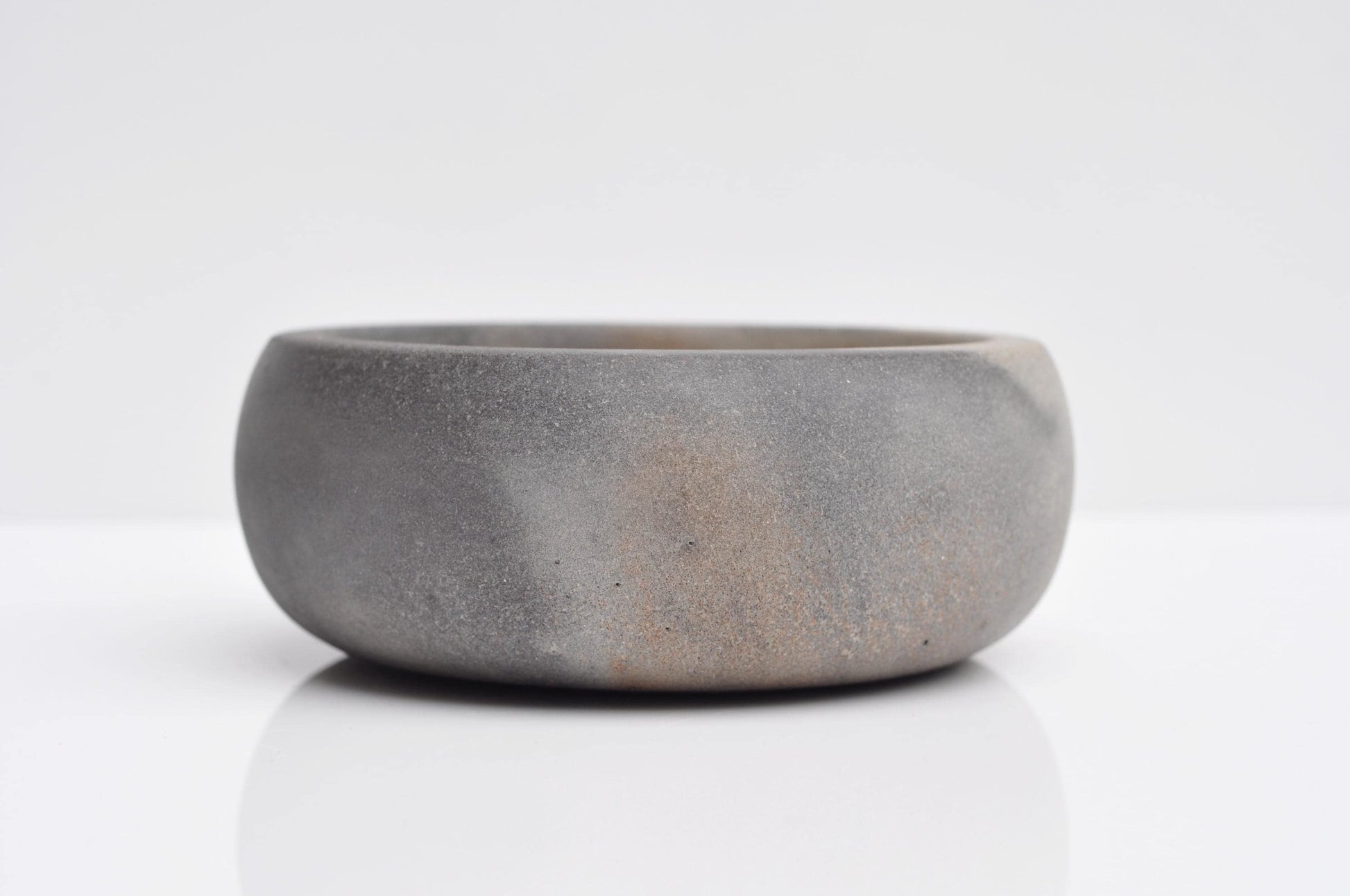 Side angle of small minimalist concrete bowl with cork feet