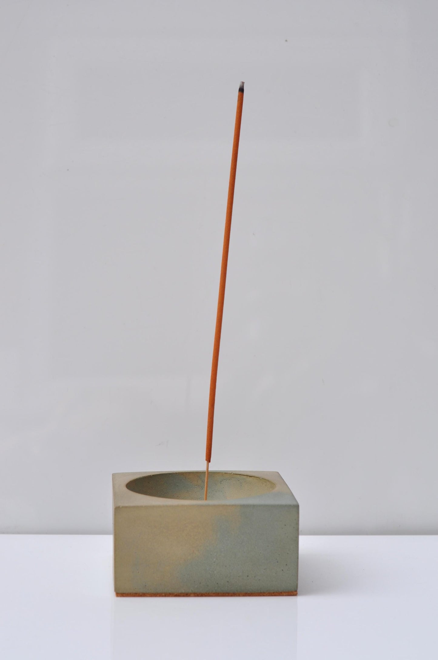 Handmade concrete incense burner holding incense stick