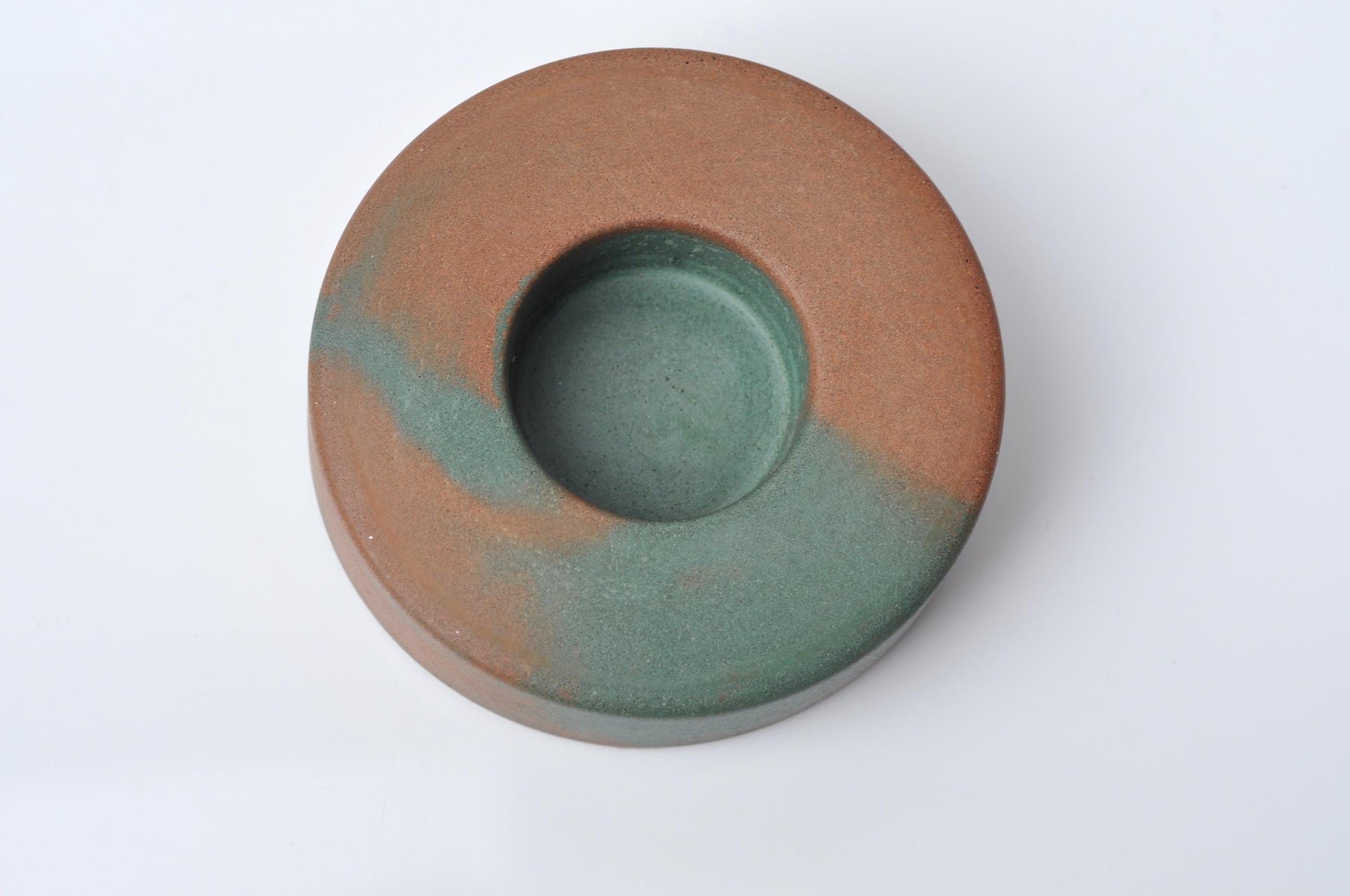 Round cement candle dish with two-tone brown and green color on a white background