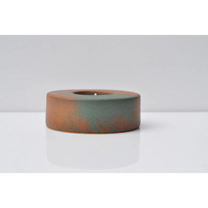 Concrete candle holder with copper accents on a white background