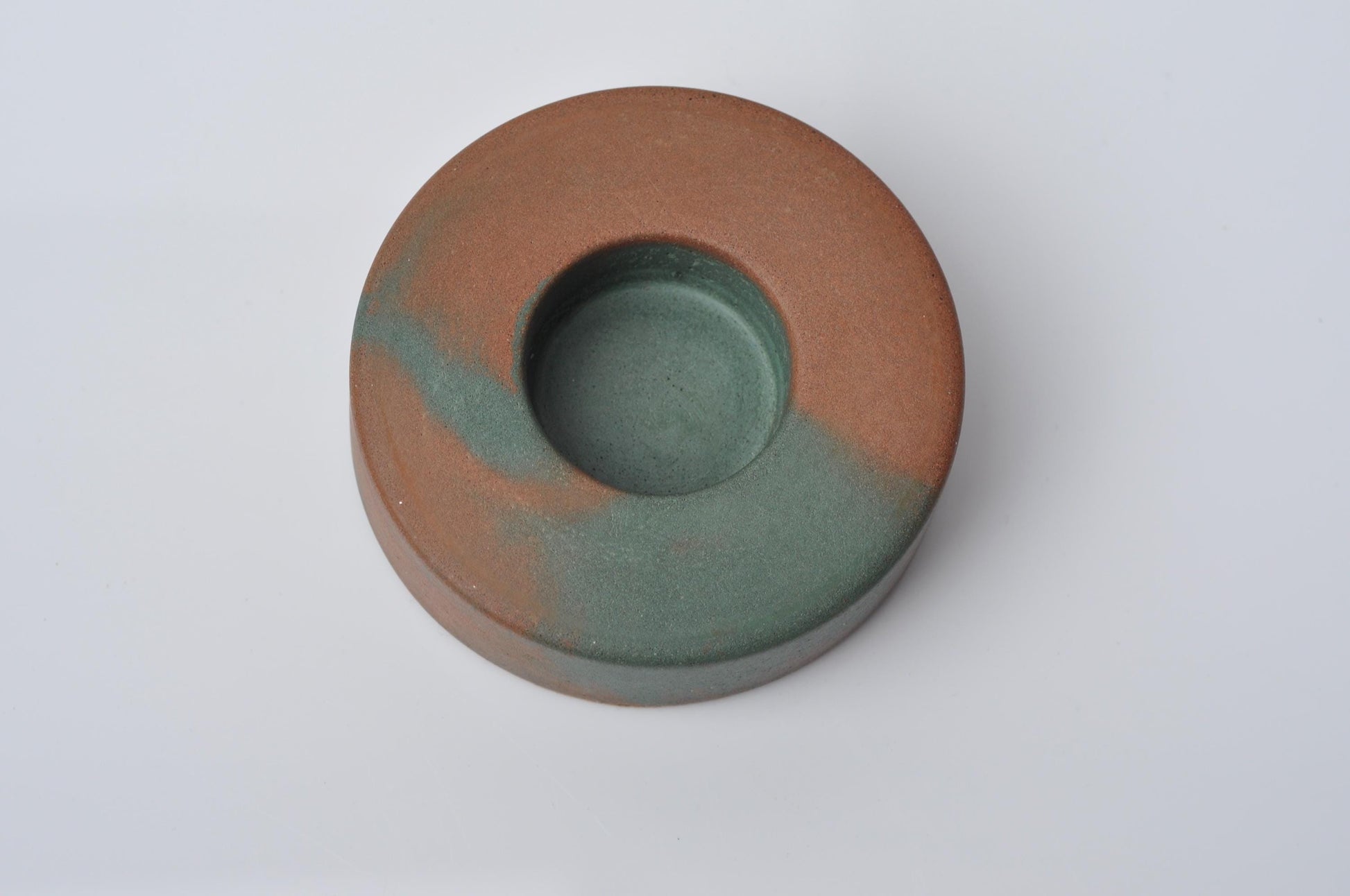 Round concrete candle holder with two-tone brown and green color on a white background