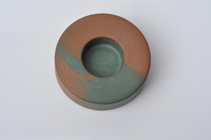 Round concrete candle holder with two-tone brown and green color on a white background