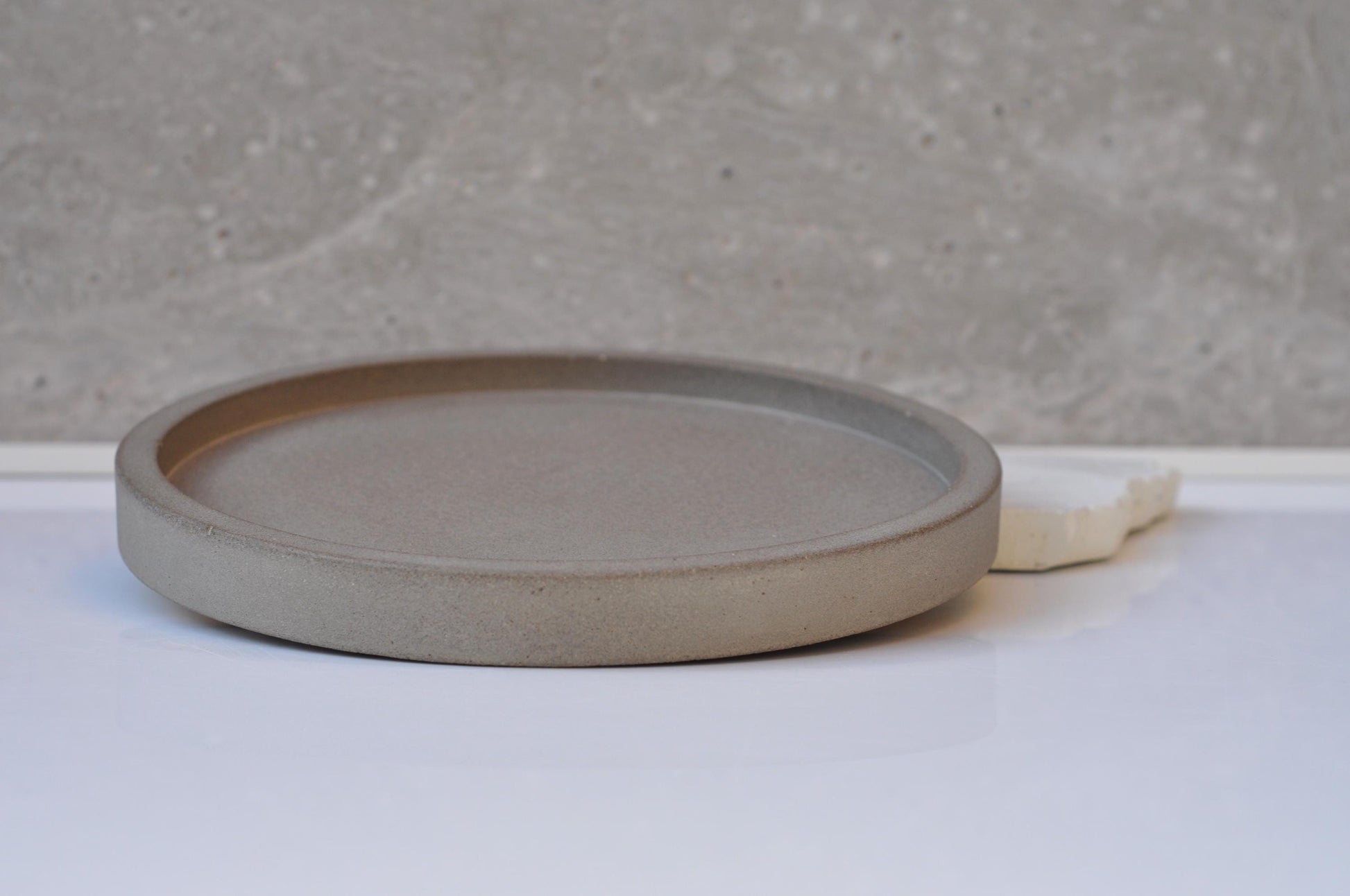 Round concrete plate on a white surface with a gray background
