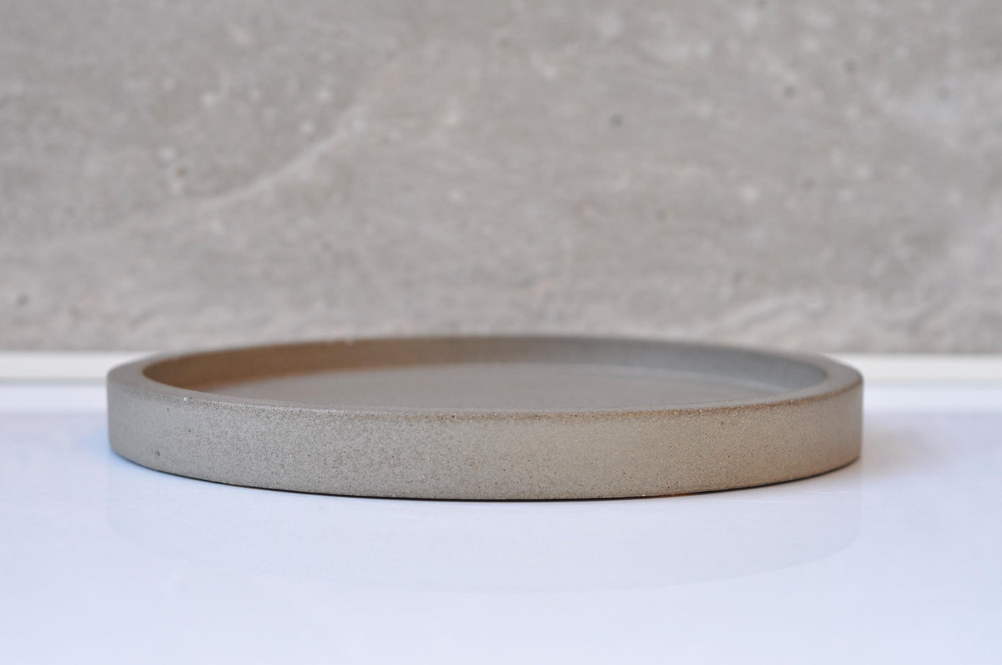 Round cement  plate on a white surface with a gray textured background