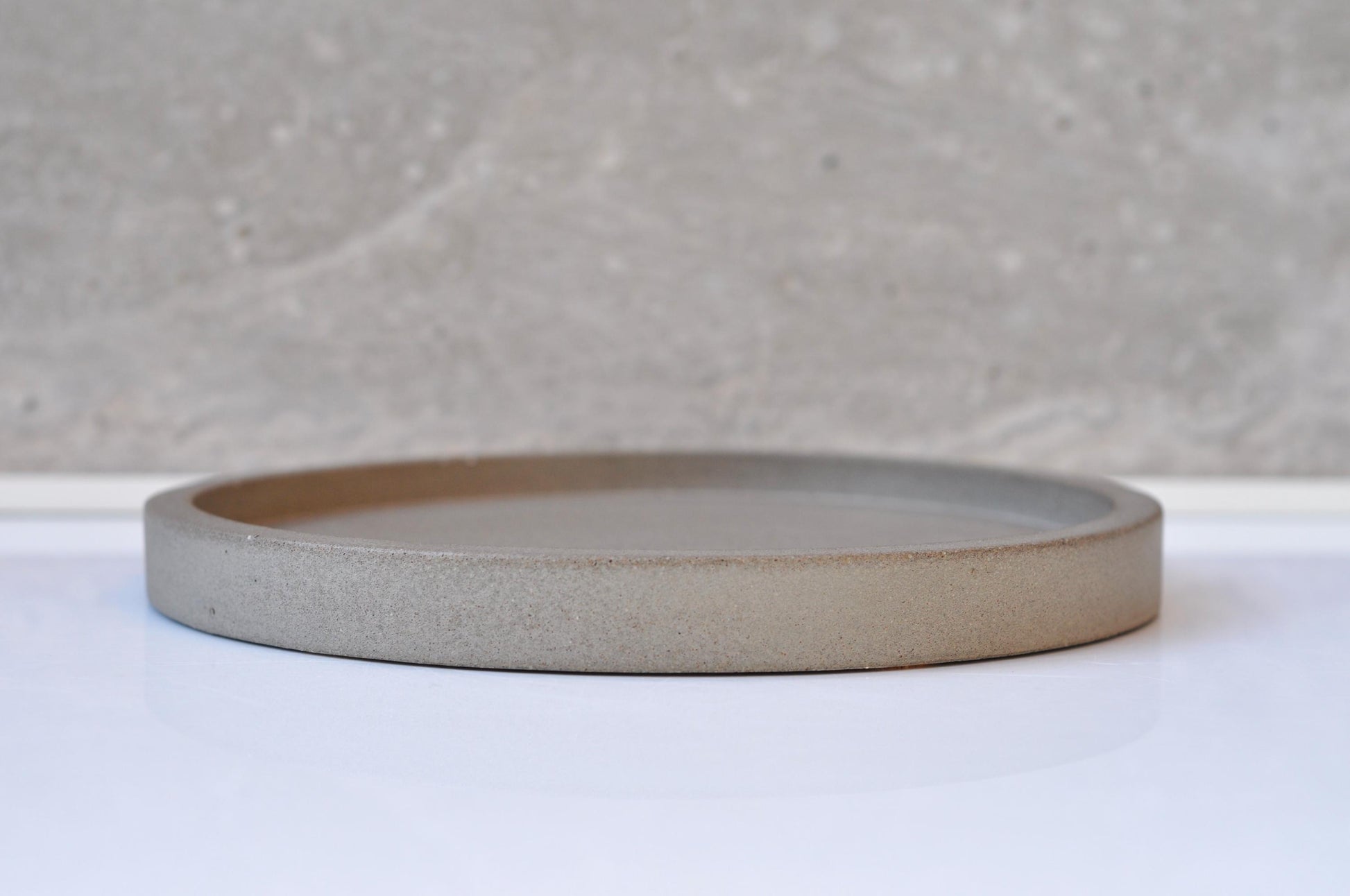 Round cement  plate on a white surface with a gray textured background