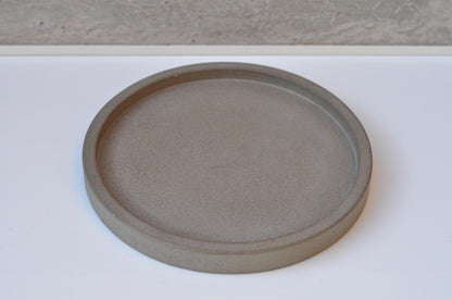 Round cement dish on a white surface with a neutral background