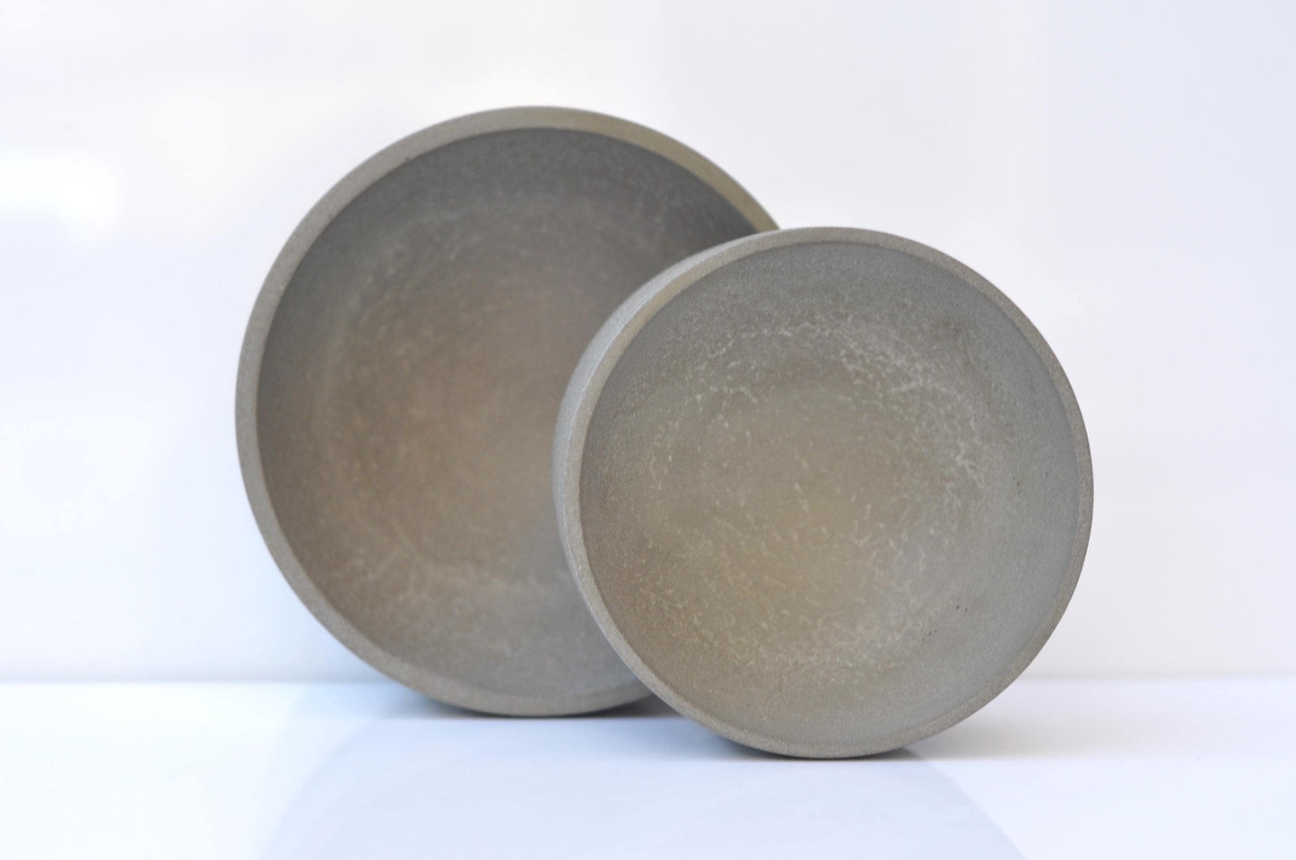 Two gray cement bowls on a white background