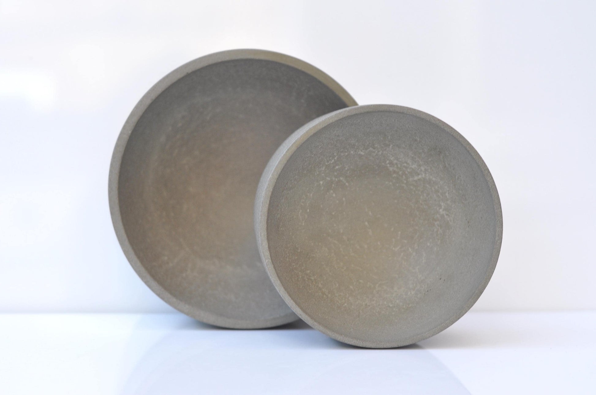 Two gray cement bowls on a white background