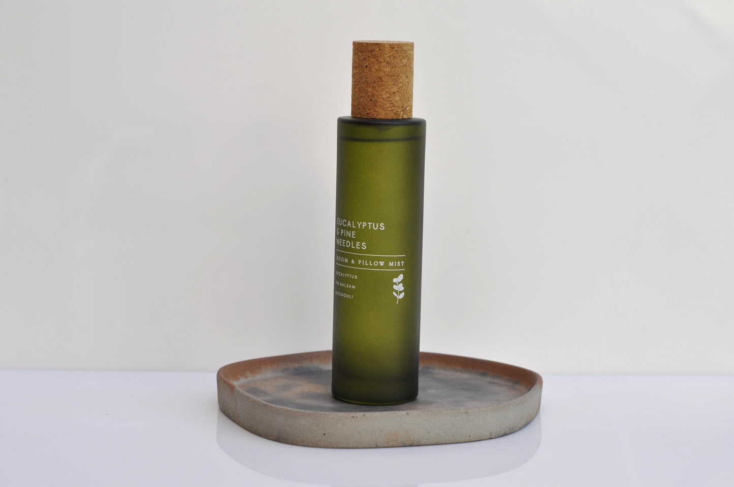 Green bottle with cork cap on a concrete coaster against a white background