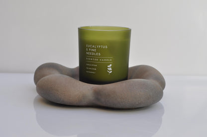 Green candle with text on a gray stone holder against a white background