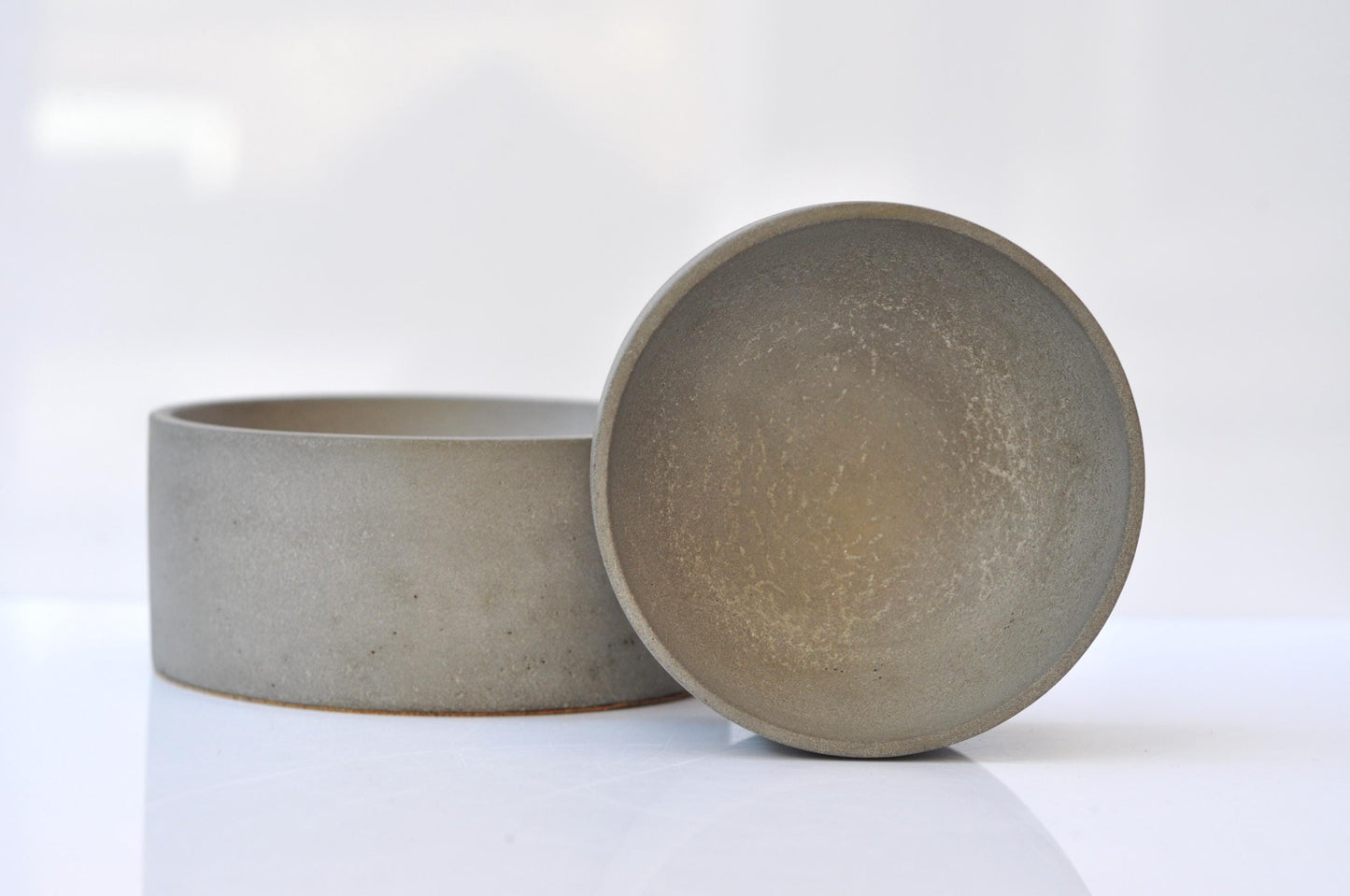 Two gray cement bowls on a white background