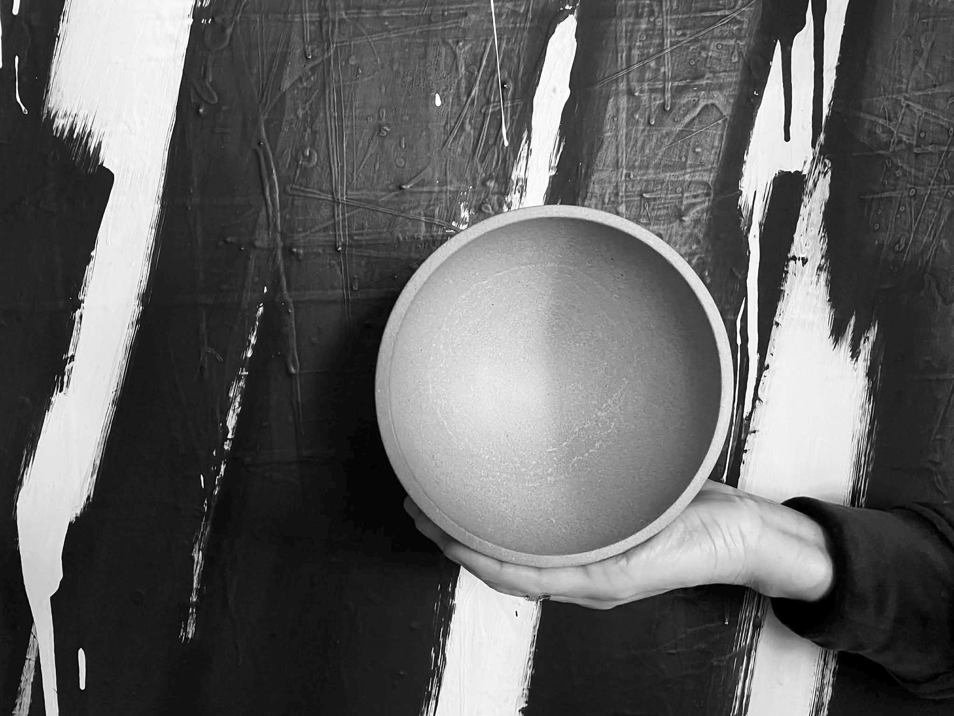 Person holding a cement  bowl against a black and white abstract background