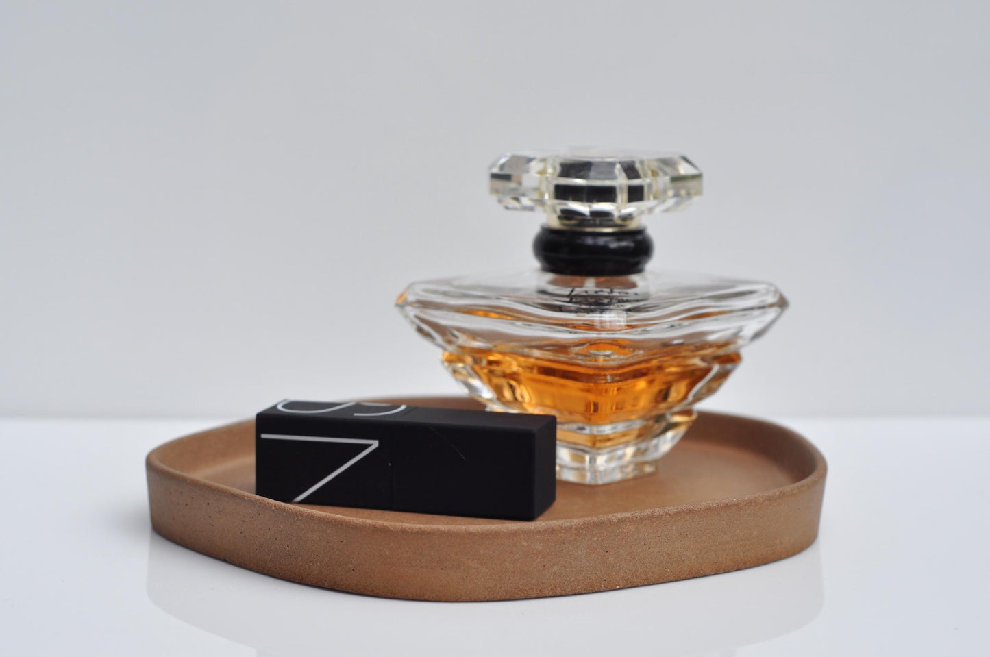 Perfume bottle with a cement tray and black box on a light gray background