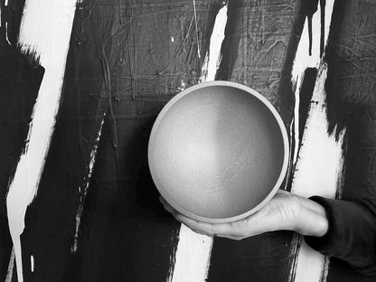 Person holding a cement bowl against a black and white abstract background