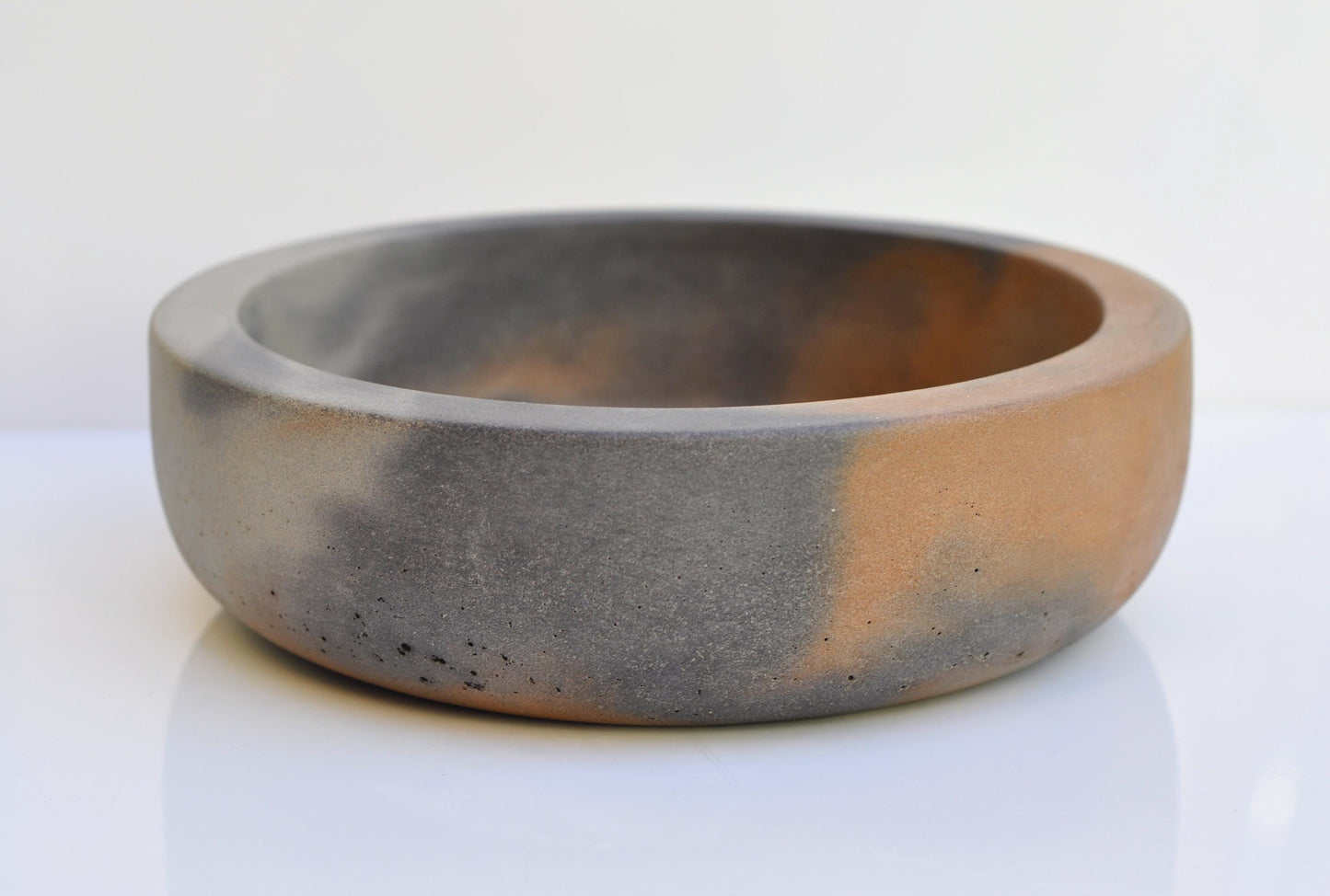 Thick heavy concrete bowl with orange interior and grey exterior