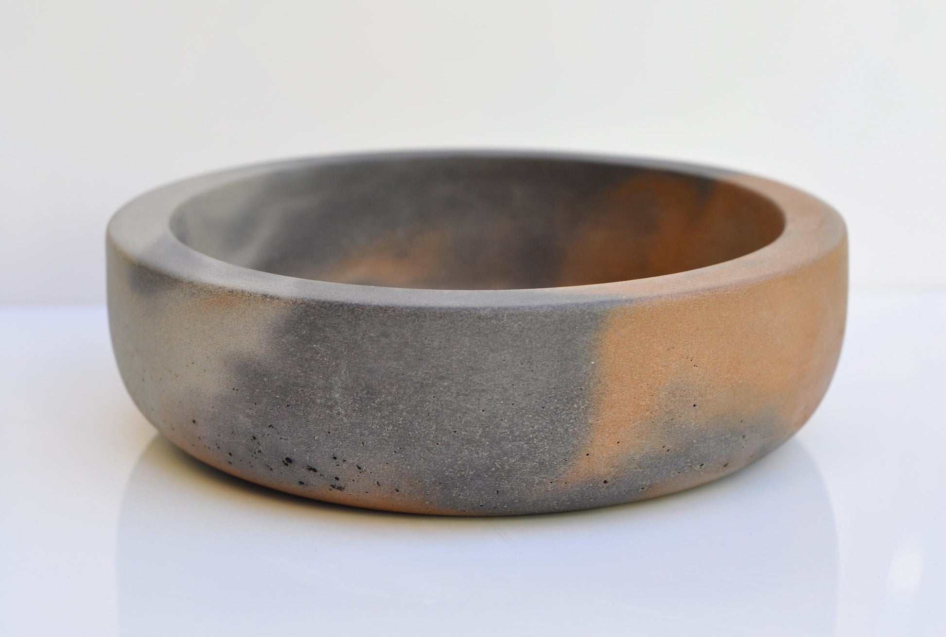 Thick heavy concrete bowl with orange interior and grey exterior