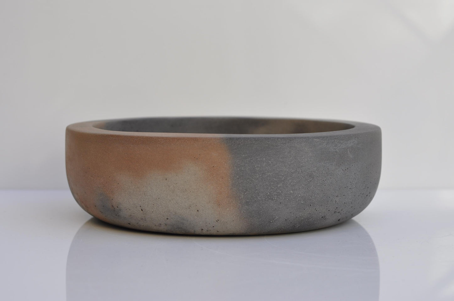 Minimalist concrete fruit bowl with two-tone grey and orange finish