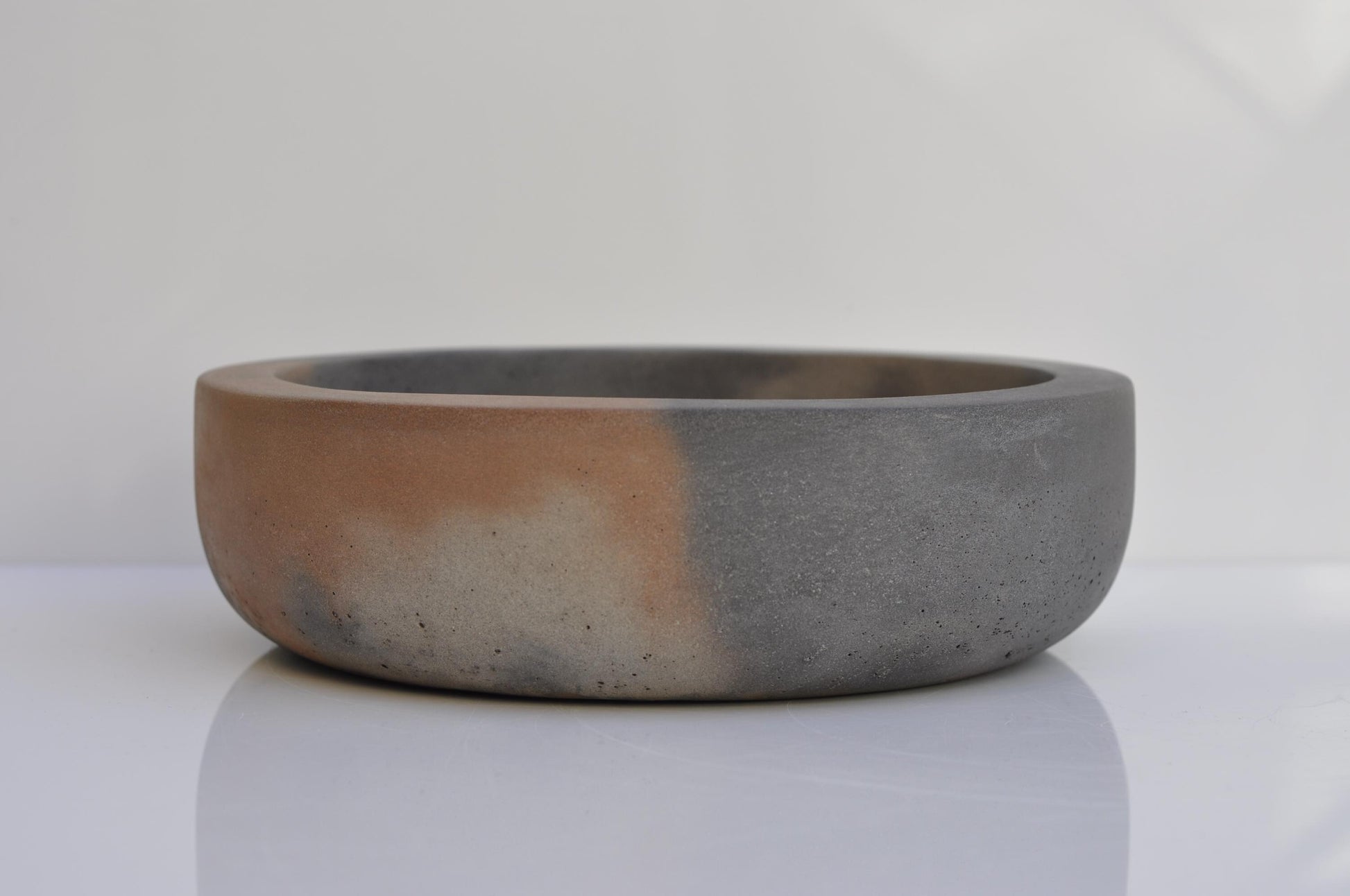 Minimalist concrete fruit bowl with two-tone grey and orange finish