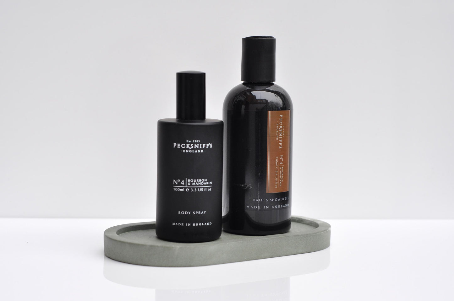 Two black bottles with labels on a gray tray against a white background