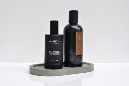 Two black bottles with labels on a gray tray against a white background