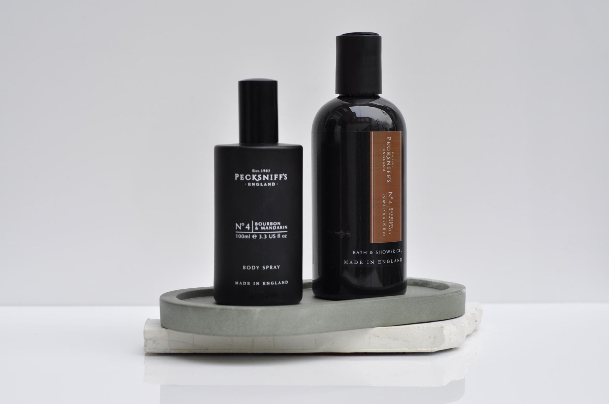 Two black bottles with labels on a gray tray against a white background