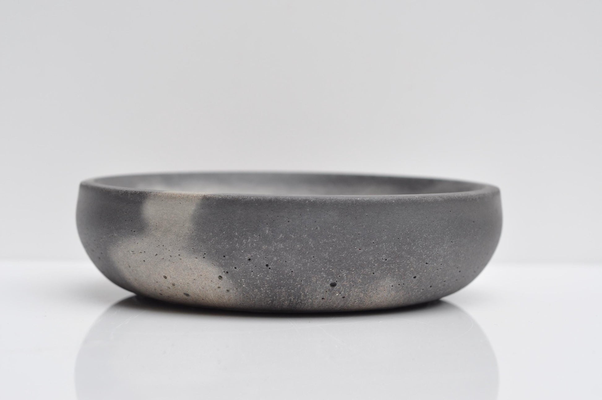 Concrete bowl holding rings and coins on desk