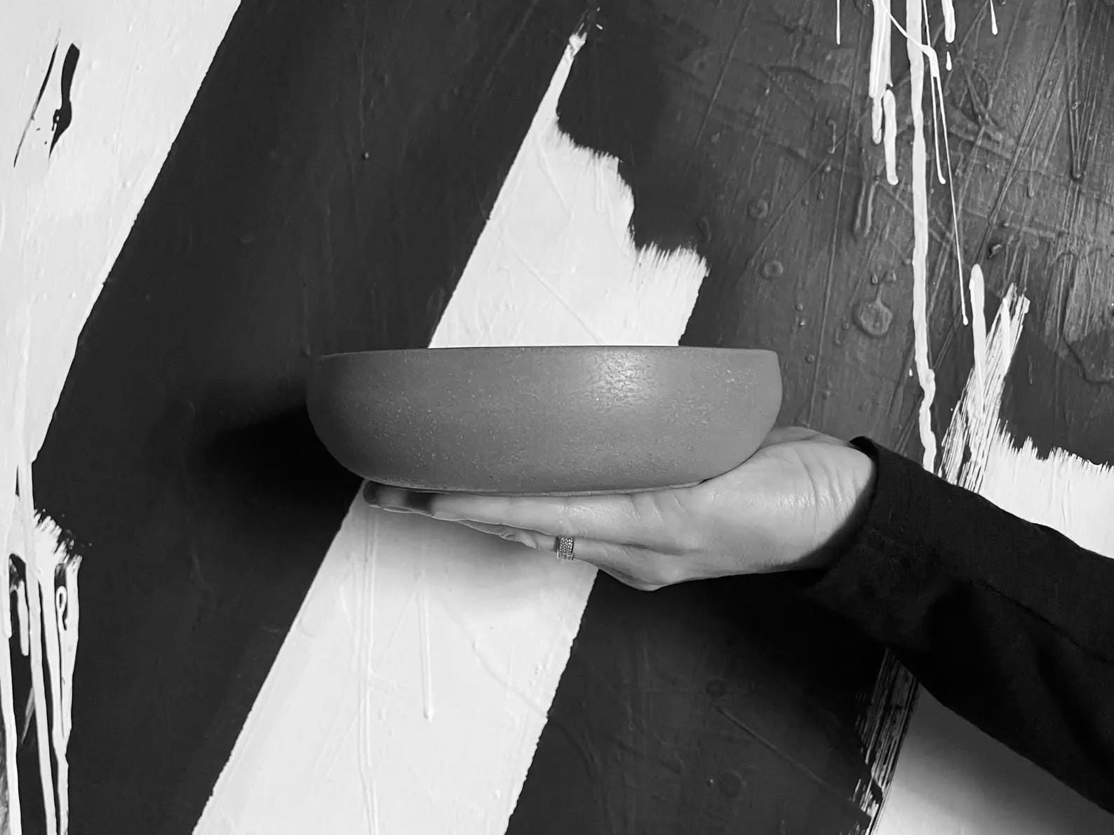 Person holding a cement bowl against a black and white abstract background