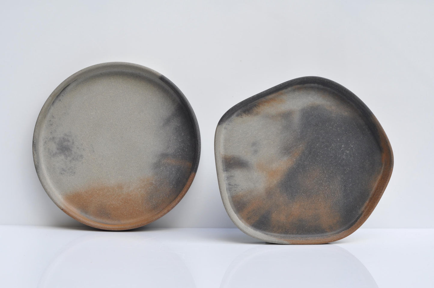 Two cement plates with a rustic, uneven surface on a white background