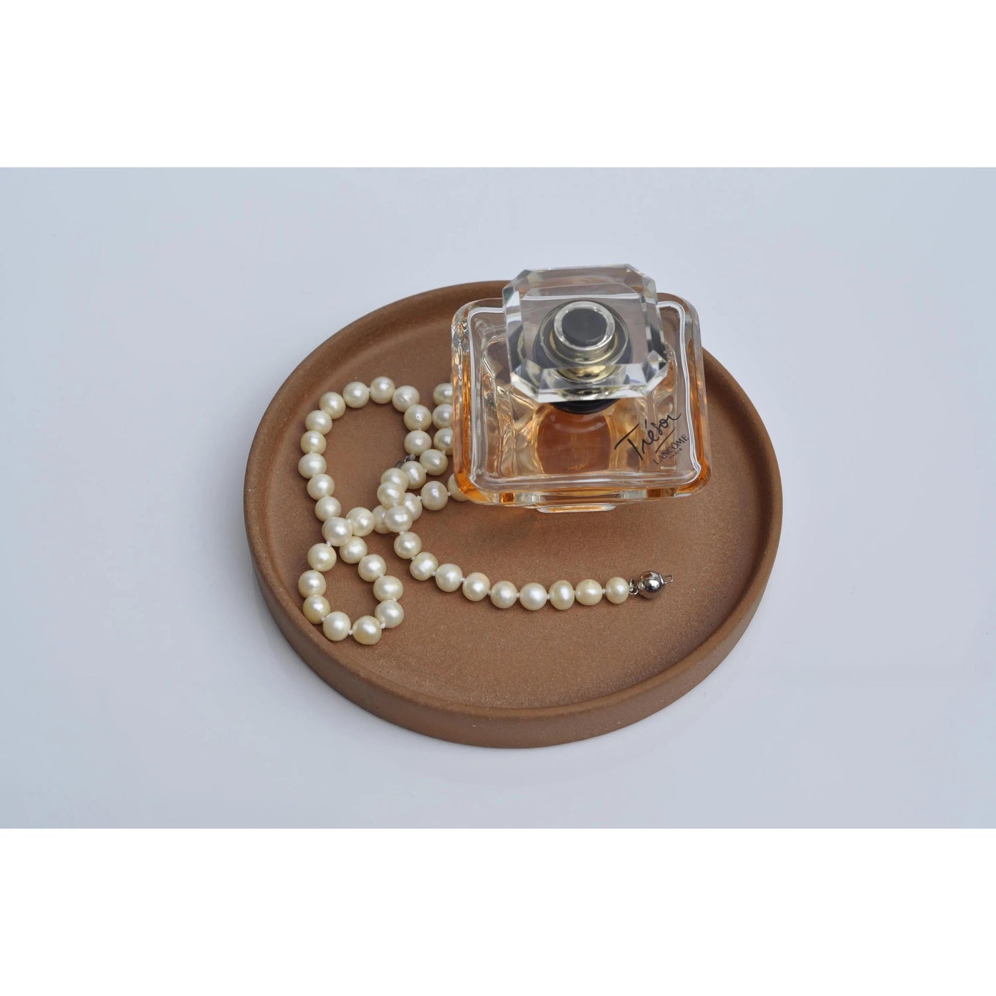 Small concrete tray holding perfume and jewellery