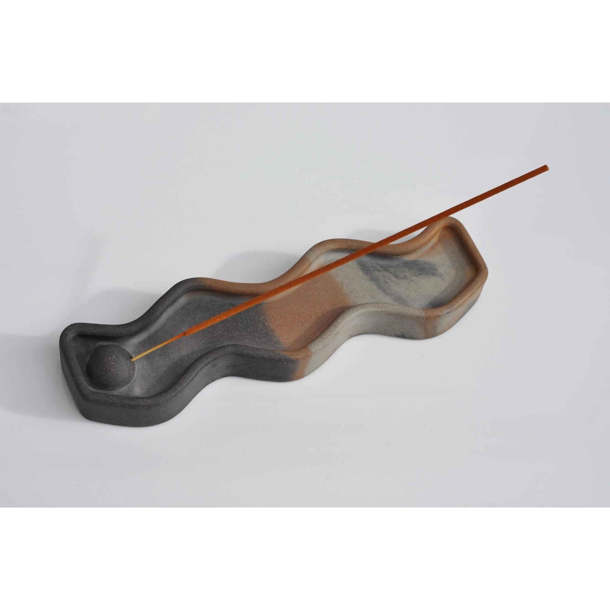 Wavy concrete  incense burner with a single incense stick on a light gray background