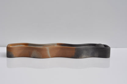 Wavy cement dish on a white surface with a gray background